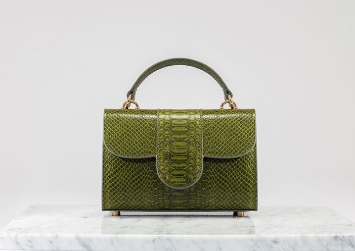 Luxury women 's bag. Luxury green leather handbag on white background, on marble floor. Crocodile skin look in green tones