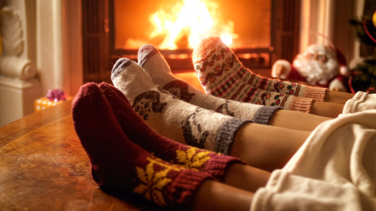 holiday traditions | close up of holiday socks on three people sitting near the fireplace