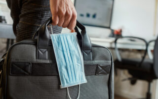 returning to the office etiquette | person holding laptop bag and mask