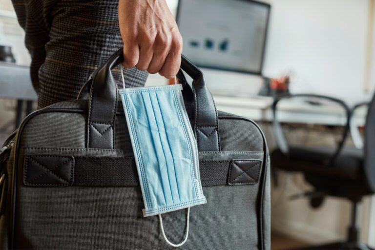 returning to the office etiquette | person holding laptop bag and mask