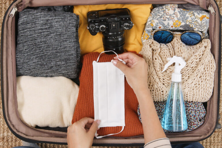 travel must-haves | overhead photo of fall suitcase with a medical face mask