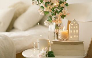 holiday houseguest etiquette for 2021 | Still life details in home interior of living room. Book, hot cup tea, candle and vase with flowers