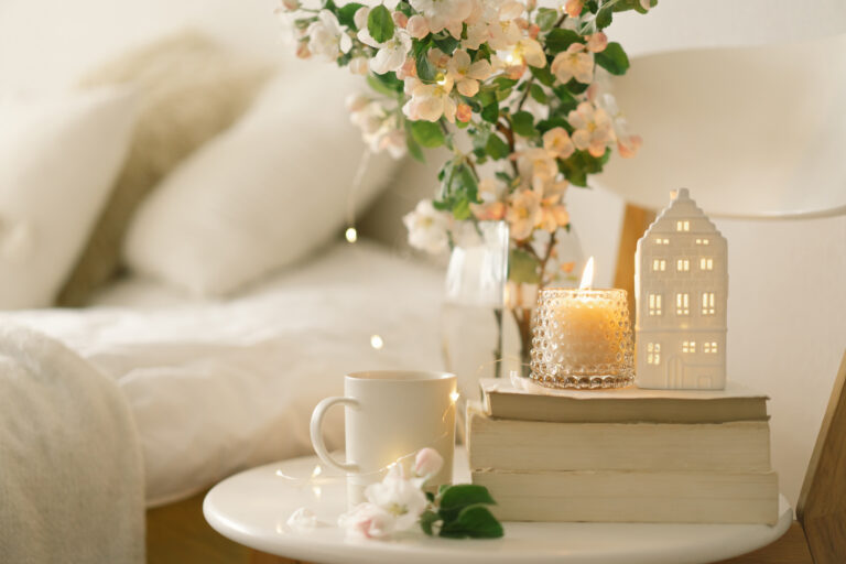 holiday houseguest etiquette for 2021 | Still life details in home interior of living room. Book, hot cup tea, candle and vase with flowers