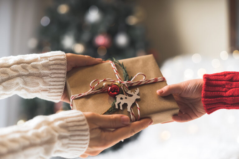 gift-giving tips | two people exchanging a holiday gift, one is wearing a sweater