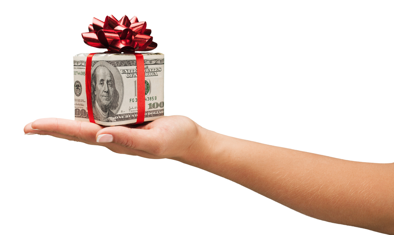 2021 Holiday Tipping Guide | Woman's hand extended with bills in the shape of a house, tied with a red ribbon