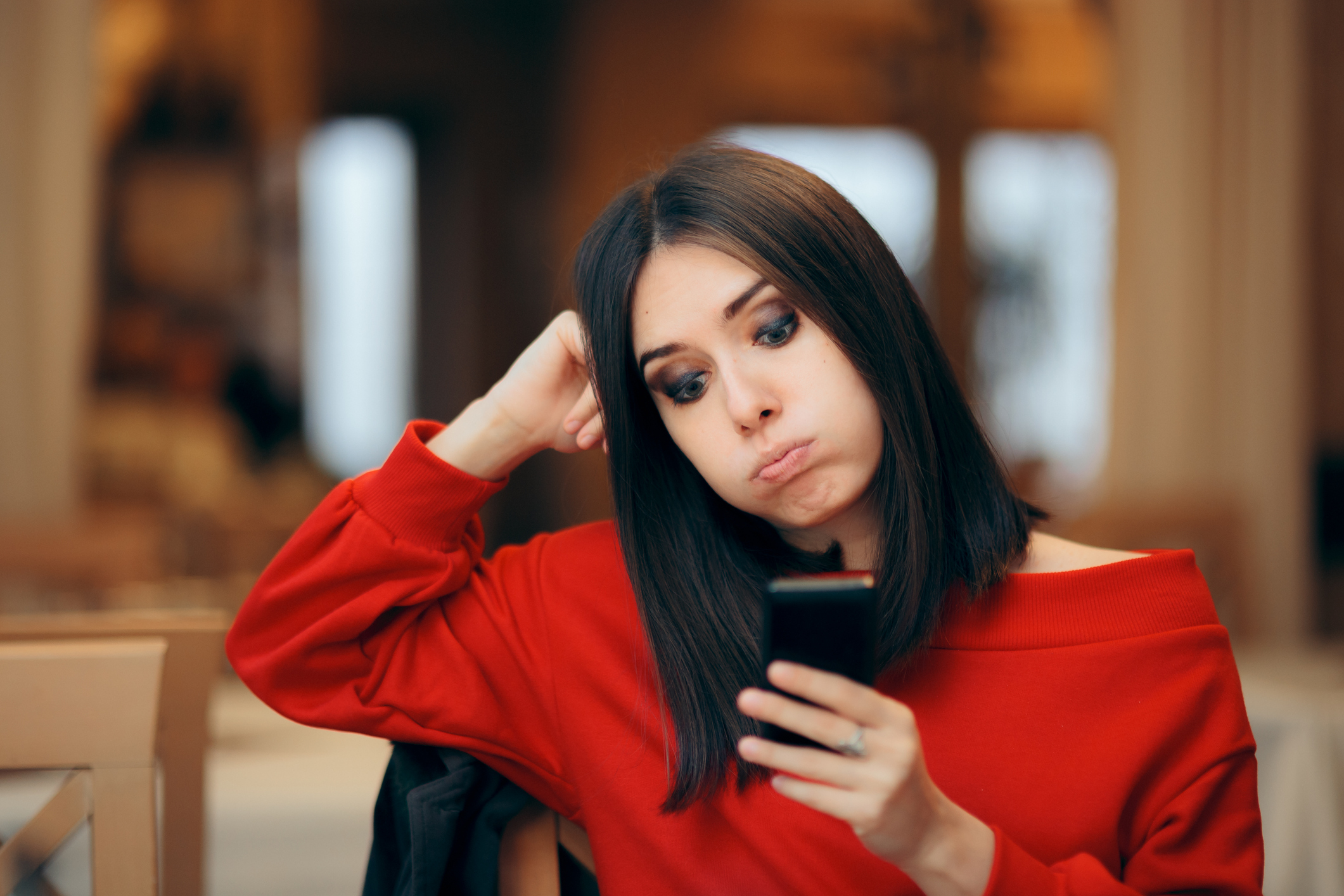 How Much Time Do You Have To Respond to a Text? | Woman in red shirt looking at her phone with a disappointed look on her face