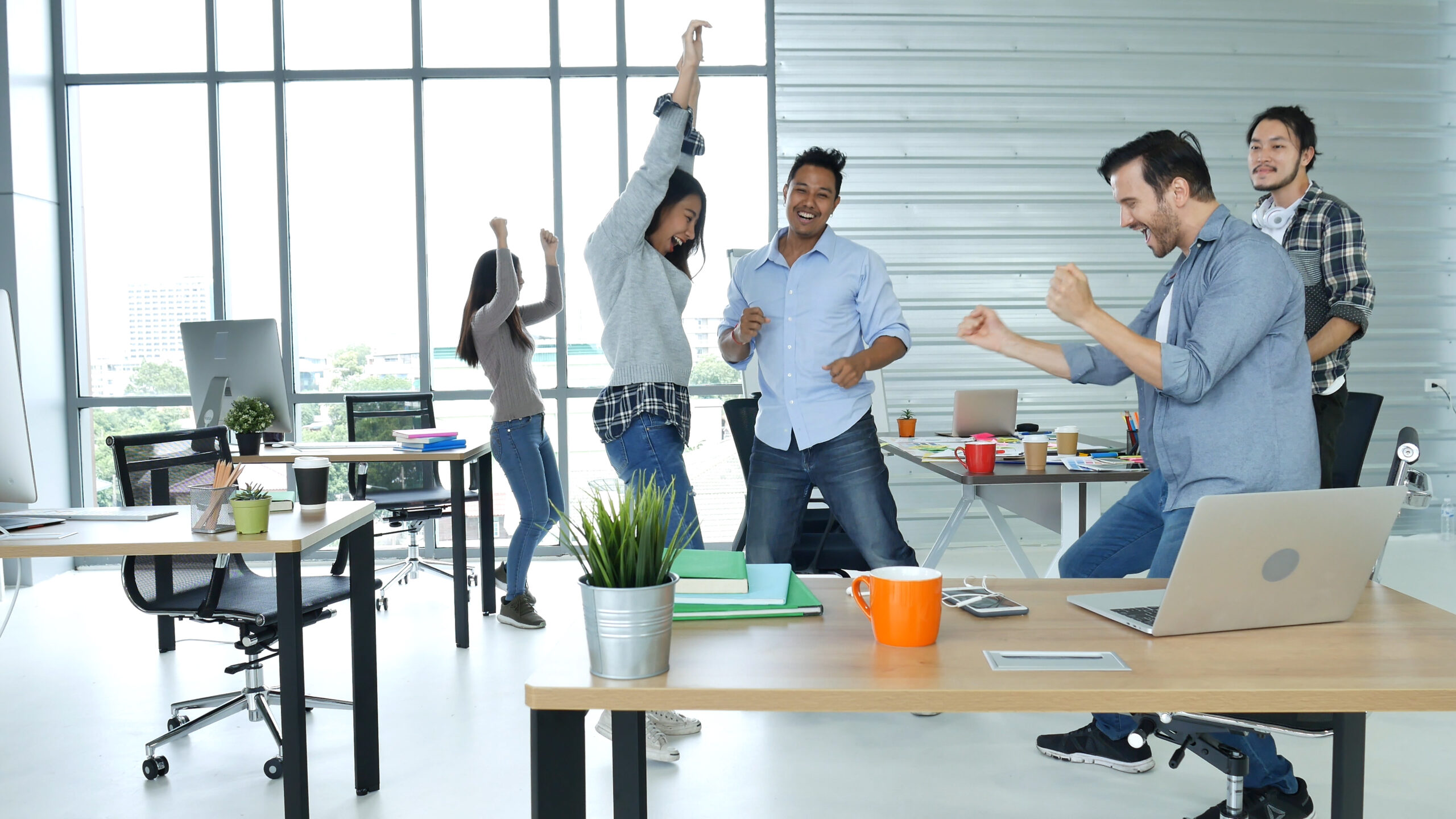 Creating More Joy in the Workplace | Employees in open office space, jumping for joy