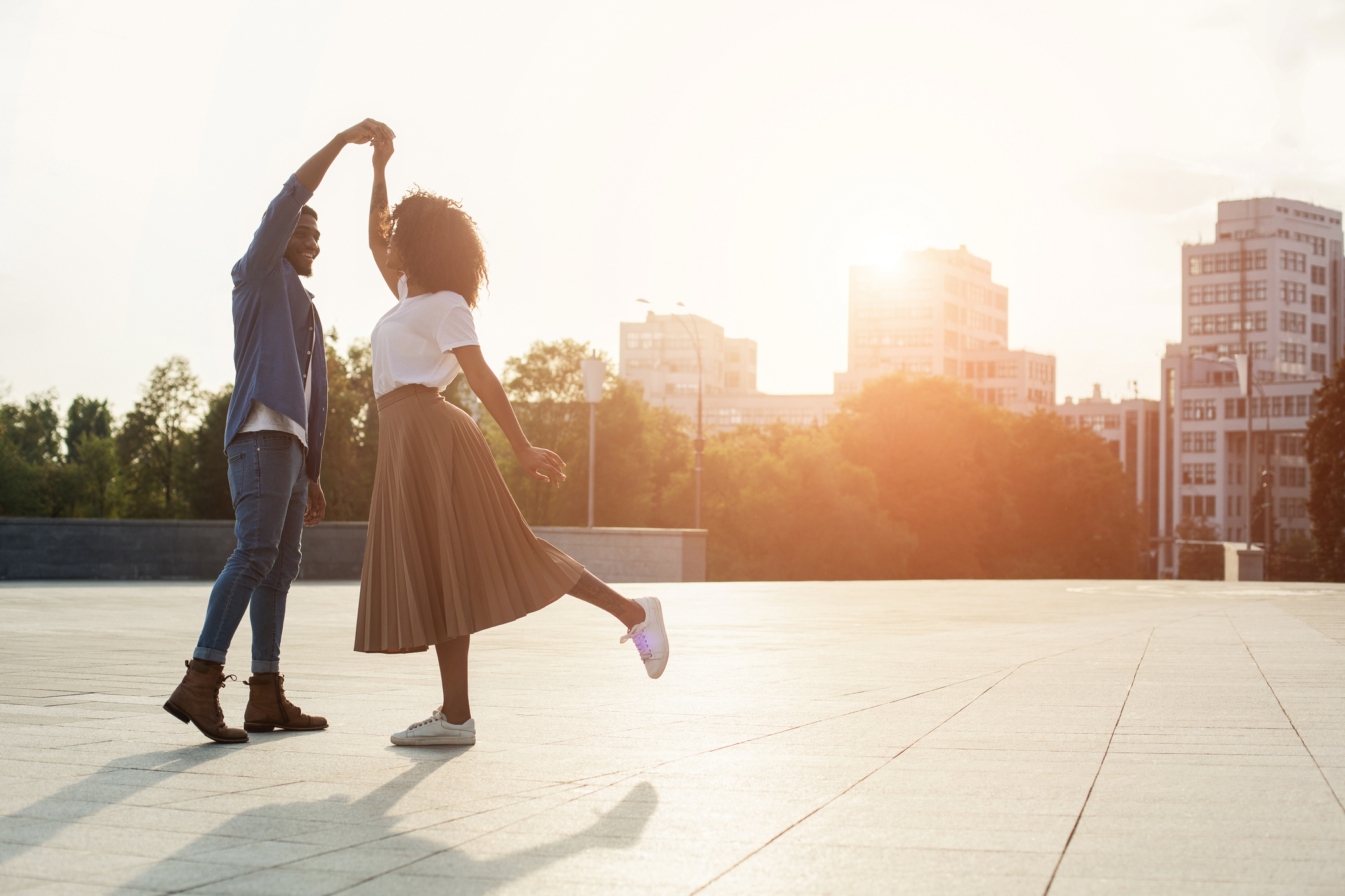 thoughtful gestures | couple dancing on street with sunshine and city skyline