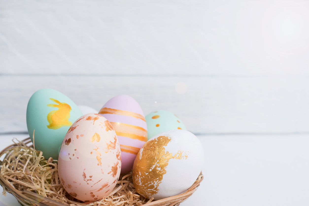 Bright easter eggs with in basket, on white wood