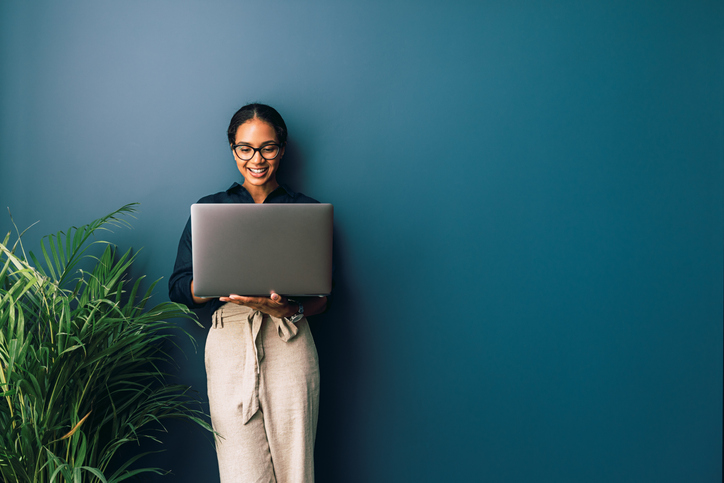 responding to emails and texts | technology etiquette | Beautiful businesswoman standing at home and holding laptop computer oh hands