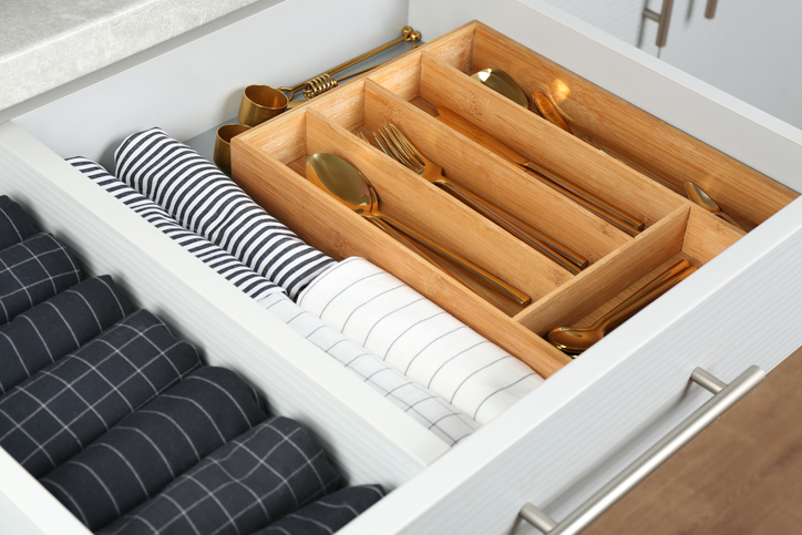 Toss these items | Open drawer with different utensils and folded towels. Order in kitchen