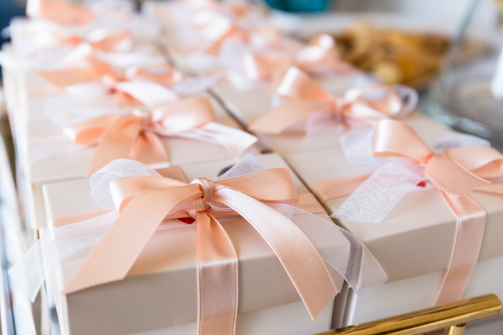 row of wedding favors in ivory boxes with blush colored bows 