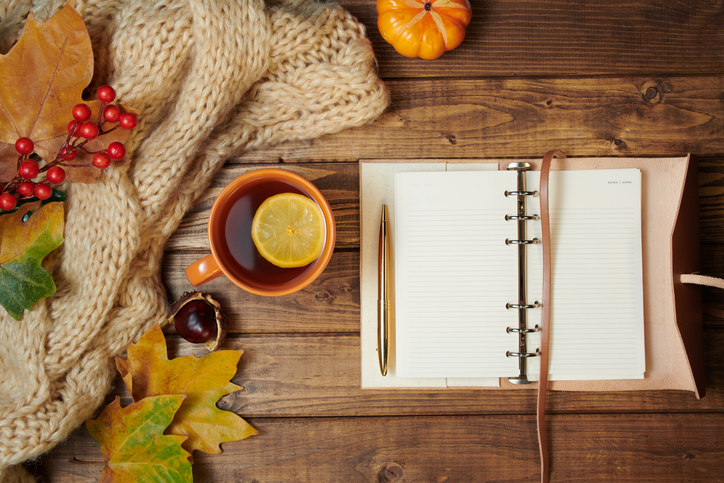 Hello october. autumn flat lay with notebook, rowan, chestnuts, leaves, tea and lemon on wooden planks.