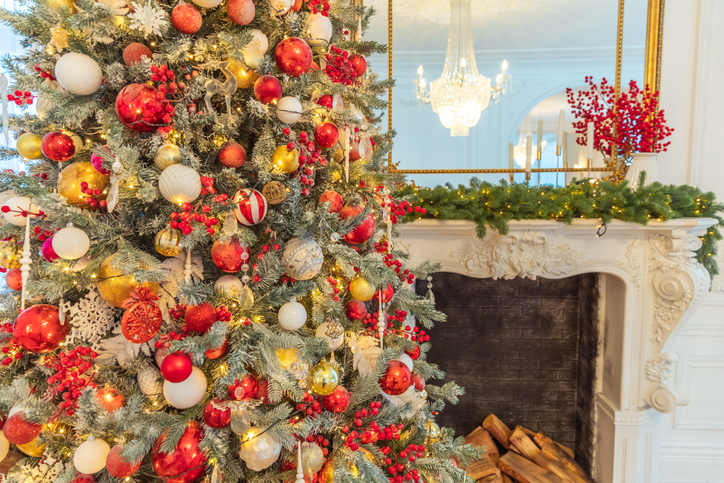 Hotel at Christmas | Classic Christmas decorated interior room, New year tree with red and gold decorations. Modern white classical style interior design apartment with fireplace and Christmas tree. 
