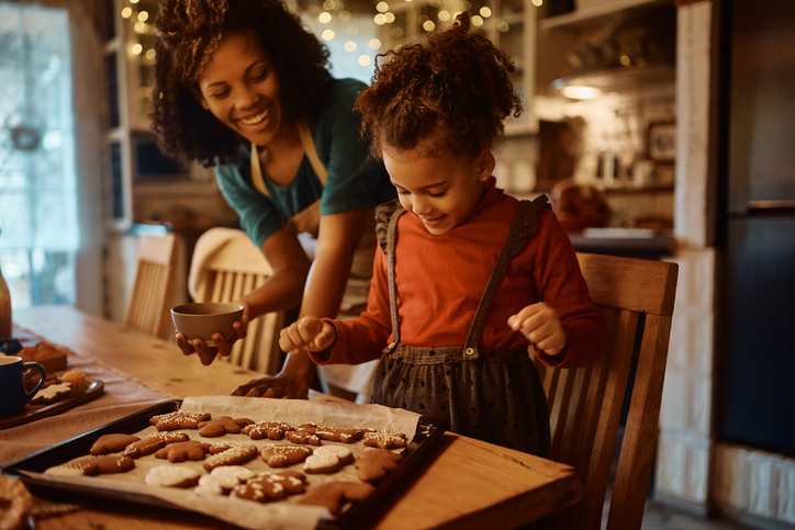 holiday gift guide for school | Happy African American mother and daughter enjoying in making gingerbread cookies for holidays in the kitchen. Focus is on girl.