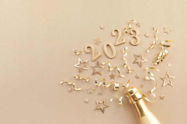 New Year's Eve Toasting Tips | Christmas and New Year background with golden champagne bottle, party decorations, confetti stars and 2023 numbers flat lay.