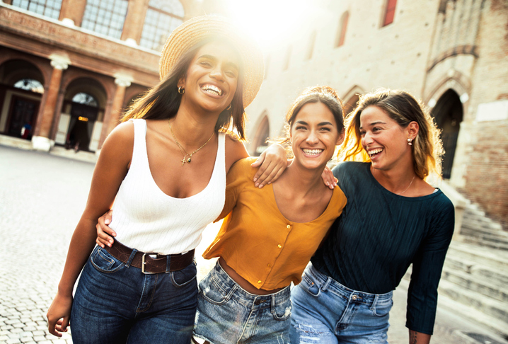 Three young diverse women having fun on city street outdoors - Multicultural female friends enjoying a holiday day out together - Happy lifestyle, youth and young females concept