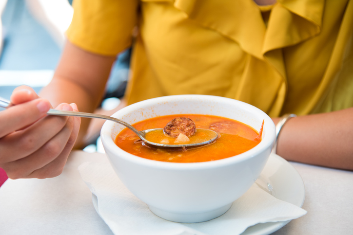 Female eating Hungarian soup with sausage in a restaurant