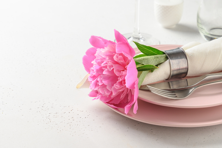 Spring romantic table setting with pink peony flowers on a white table. Close up.
