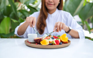 Table manners for teens | Closeup of a young woman eating mixed fruits french toast brunch in restaurant