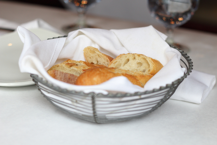 Freshly sliced country white bread in basket at restaurant table
