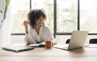 what matters more than money to employees | Smiling, happy, Young beautiful african american woman studying at home with laptop. Taking notes in notebook. Bright spacious living room. E-learning concept. Study at home concept.