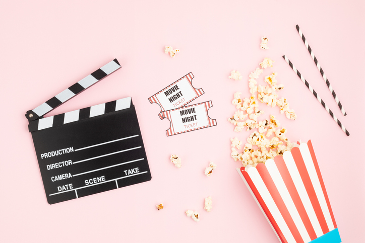 Movie clapperboard, tickets and popcorn over pink background. Movie night, home cinema, party invitation. Top view, copy space, mockup