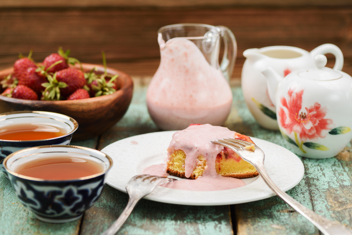 Yummy homemade cake with fresh strawberries, tea and cream sause in glass jar closeup