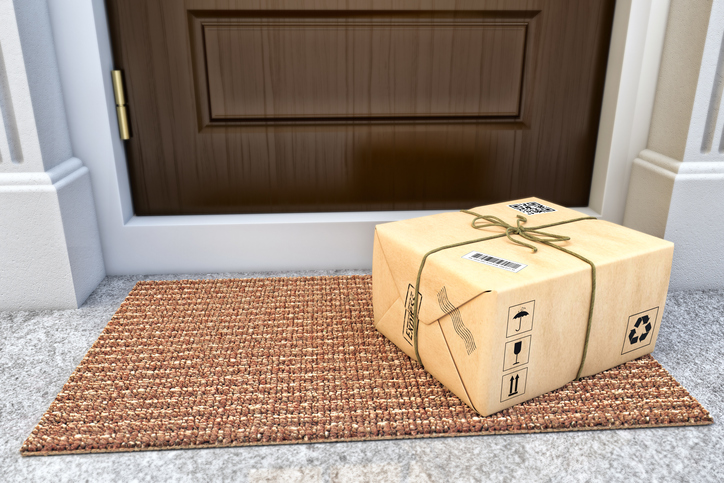 Parcel box wrapped in craft paper on the door mat near the entrance door