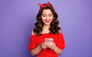 Things Not to Say in a Text Message | Texting Etiquette | Beautiful lady holding telephone, hands wear off-shoulders dress isolated purple background