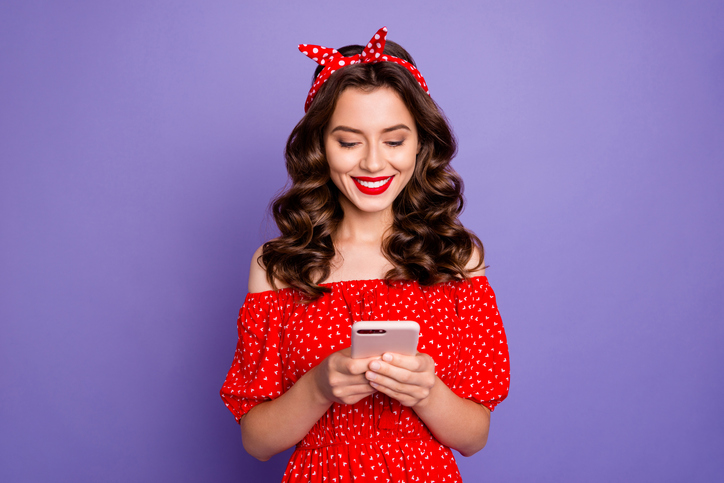 Things Not to Say in a Text Message | Texting Etiquette | Beautiful lady holding telephone, hands wear off-shoulders dress isolated purple background