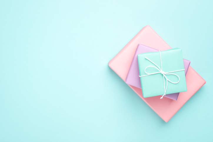 Pastel colored gift boxes on turquoise background. Minimal styled flat lay for Mother's Day, Birthday and Holiday. Books wrapped in gift paper.