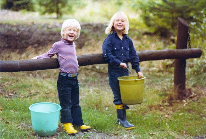 Vintage colorful 1979 image of a young boy and girl with blond hair picking blackberries in a forest.