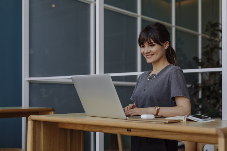 good posture | Happy young woman, casually dressed, using technology at work (copy space).