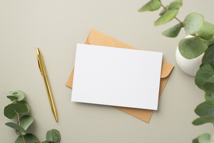 Reasons to send a handwritten note | Top view photo of paper sheet craft paper envelope gold pen and white ceramic vase with eucalyptus on pastel grey background with blank space