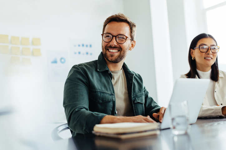 authentic smile | Happy business man listening to a discussion in an office boardroom. Business professional sitting in a meeting with his colleagues.