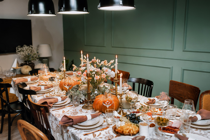 Hosting a Fall Cocktail Party | The Thanksgiving dinner table. A traditional Thanksgiving or Friendship Day party. Decoration and serving of the festive table with autumn decor, candles and flowers dishes and pumpkins.