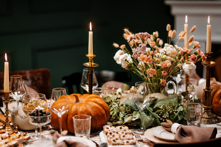 Hosting a Fall Cocktail Party | The Thanksgiving dinner table. A traditional Thanksgiving or Friendship Day party. Decoration and serving of the festive table with autumn decor, candles and flowers dishes and pumpkins.