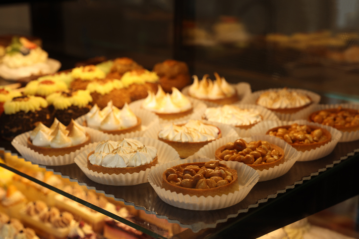 Different tasty tartlets on counter in bakery shop, closeup. Space for text