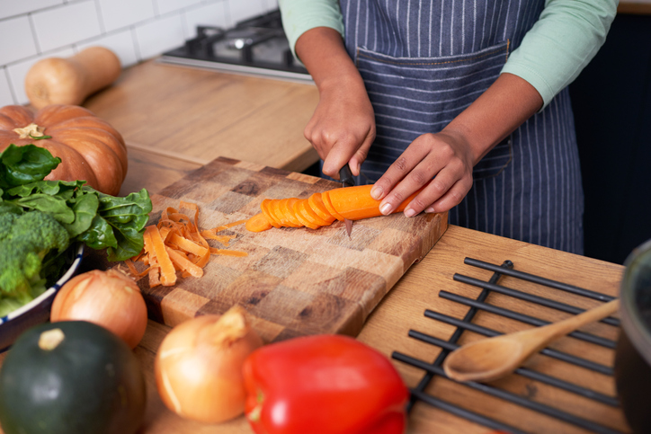 Close up of young woman chopping carrots for vegan soup or stew. High quality photo