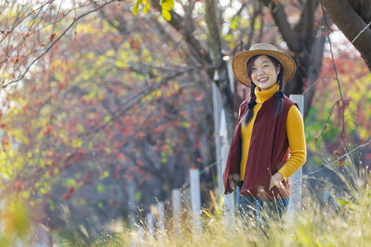 Happy Asian farmer girl portrait in autumnal fashion with fall color from maple tree during harvest season