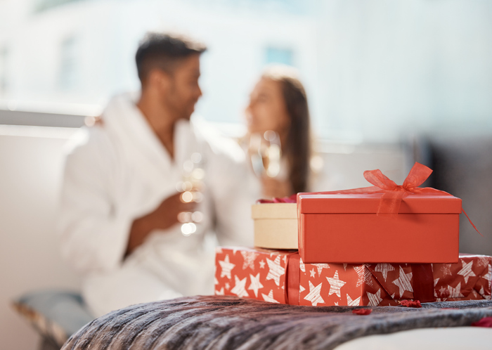 Christmas gift, present and happy couple celebrate the holiday at hotel with champagne. 