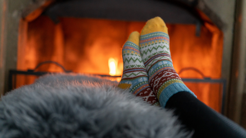 Female legs with colorful socks near a fireplace