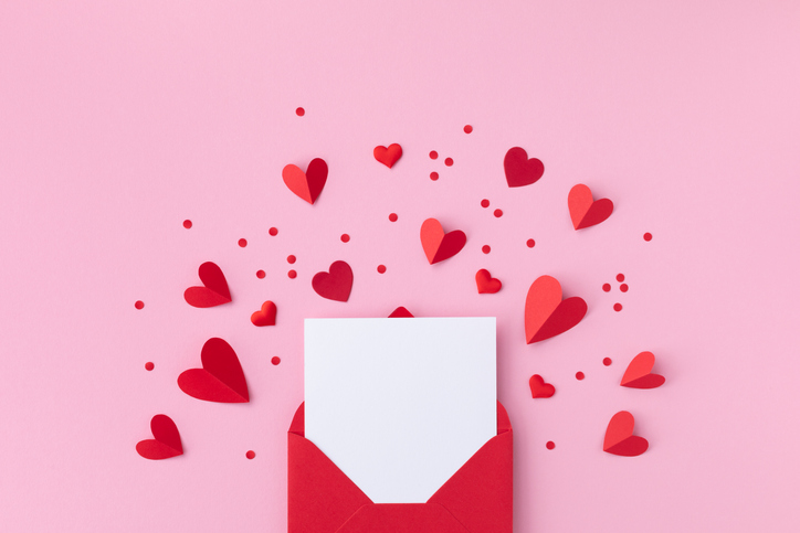 Saint Valentine day holiday background with envelope, paper card and various red hearts for love romantic message. Flat lay composition.