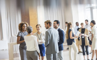 Networking skills | Group of business people standing in hall, smiling and talking together