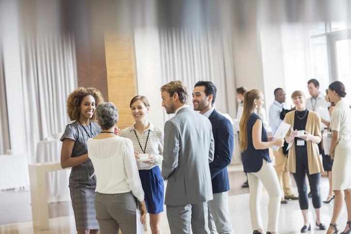 Networking skills | Group of business people standing in hall, smiling and talking together