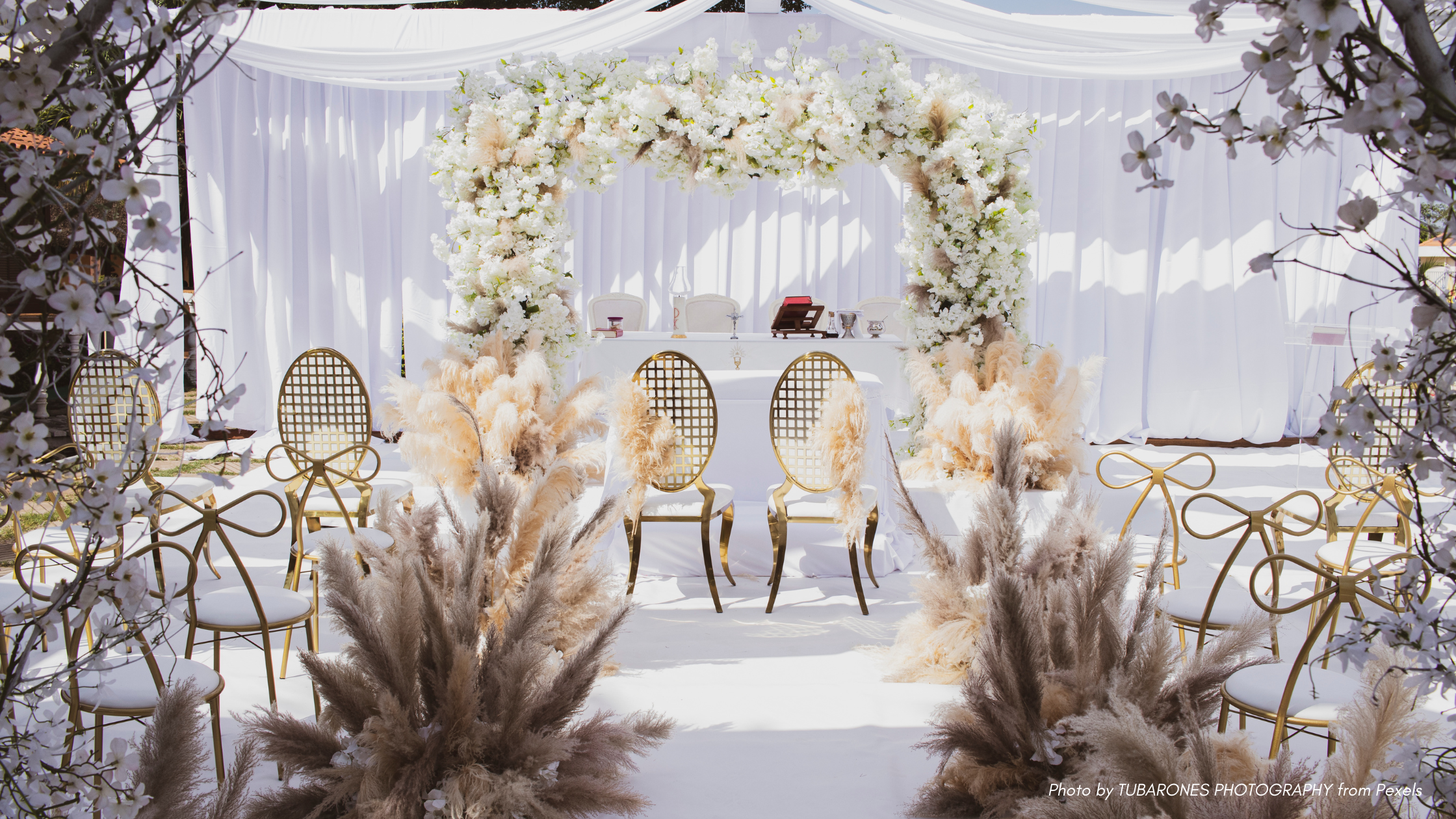 Wedding Etiquette Questions | An elegant wedding reception in whites and cream colors with bow shaped chair backs