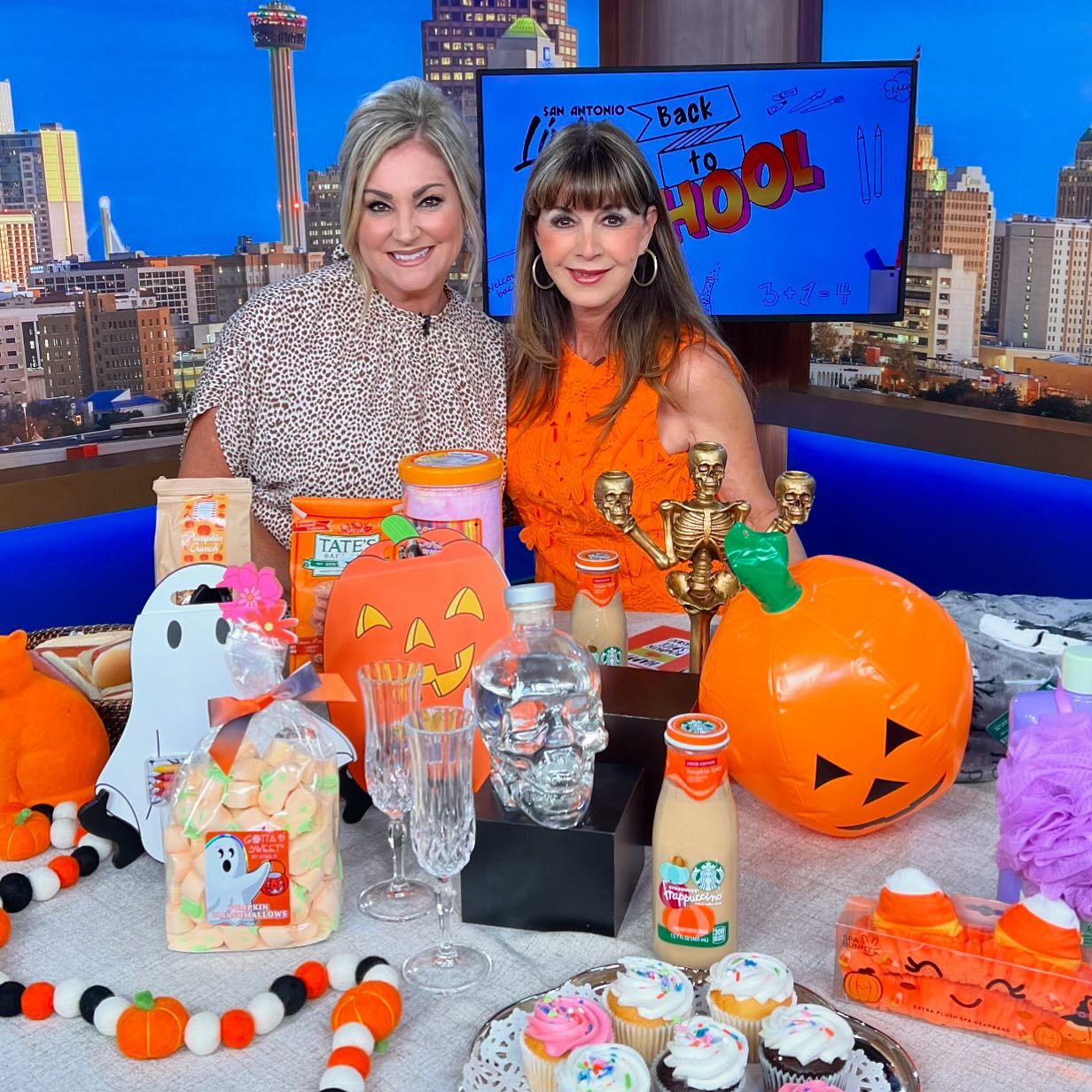 Summerween Party Tips from Etiquette Expert Diane Gottsman | Diane Gottsman and Shelly Miles on the set of San Antonio Living posing behind a table of Summerween party essentials in bright orange and fall colors