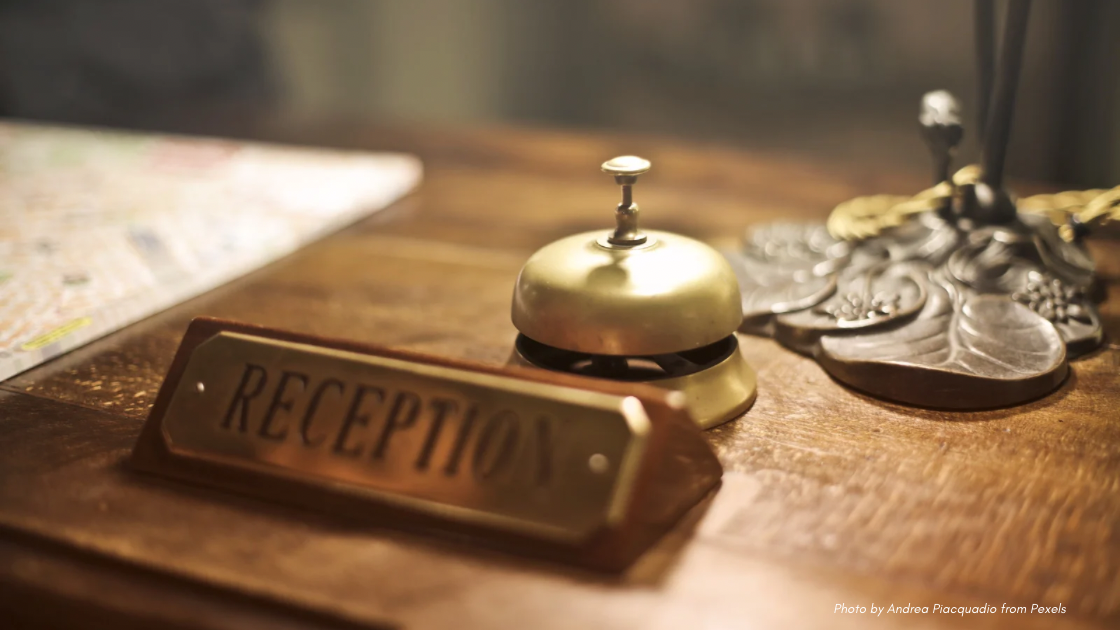 Hotel Etiquette Reminders | Hotel Front Desk with Brass Bell and Reception Sign