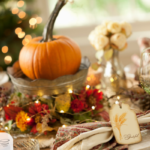 Thanksgiving Host Etiquette | table set for Thanksgiving with pumpkins, flowers, and lights